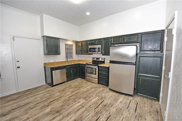 kitchen featuring a textured ceiling, stainless steel appliances, light hardwood / wood-style floors, and sink