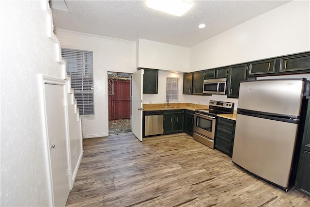 kitchen featuring a textured ceiling, sink, light wood-type flooring, and appliances with stainless steel finishes