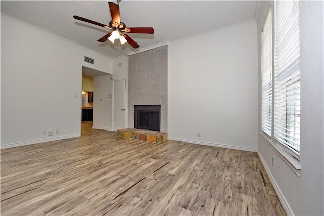 unfurnished living room with a textured ceiling, ceiling fan, crown molding, a fireplace, and light hardwood / wood-style flooring