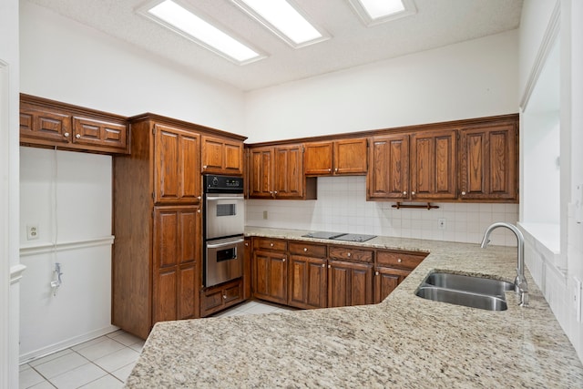 kitchen featuring sink, light stone counters, double oven, decorative backsplash, and light tile patterned flooring