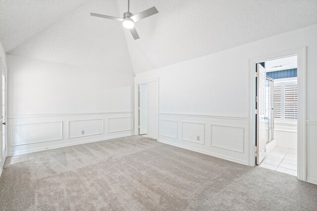 carpeted empty room featuring a textured ceiling, ceiling fan, and lofted ceiling