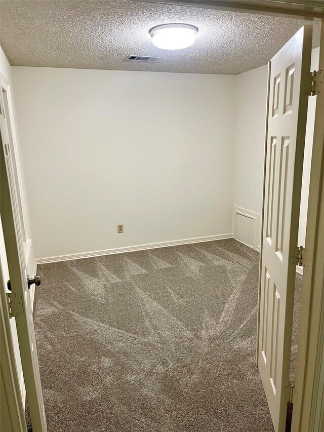 carpeted empty room featuring a textured ceiling