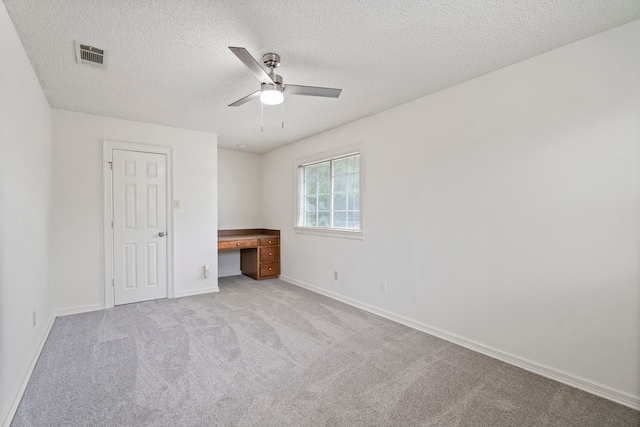 unfurnished bedroom with light carpet, a textured ceiling, and ceiling fan