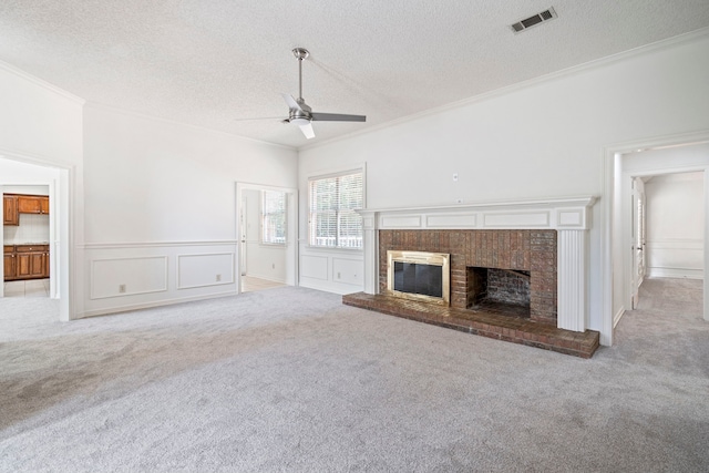 unfurnished living room with ceiling fan, crown molding, light carpet, and a brick fireplace