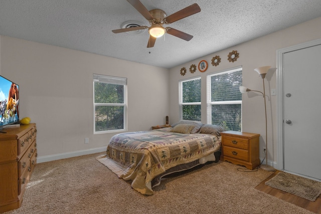 carpeted bedroom featuring ceiling fan, multiple windows, and a textured ceiling