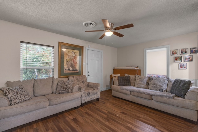 living room featuring dark hardwood / wood-style flooring, a textured ceiling, and ceiling fan