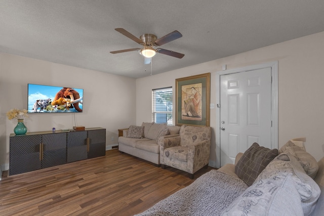 living room featuring dark wood-type flooring, a textured ceiling, and ceiling fan