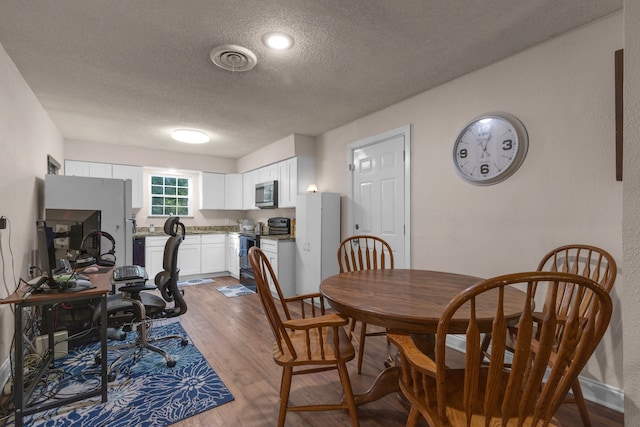 dining room featuring wood-type flooring and a textured ceiling