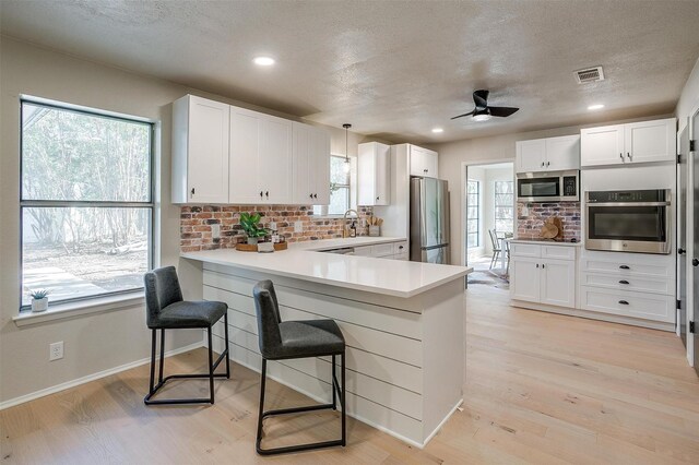 kitchen with white cabinets, appliances with stainless steel finishes, and kitchen peninsula