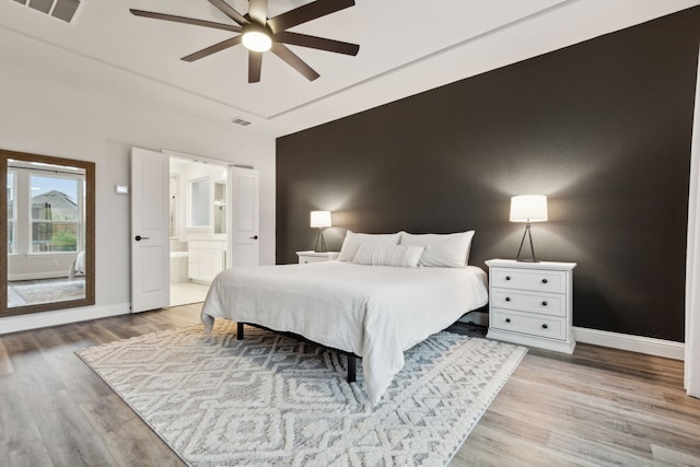 bedroom featuring hardwood / wood-style floors, ensuite bath, and ceiling fan