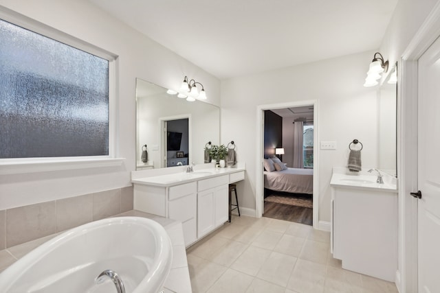 bathroom featuring tile patterned flooring, vanity, a healthy amount of sunlight, and a tub to relax in