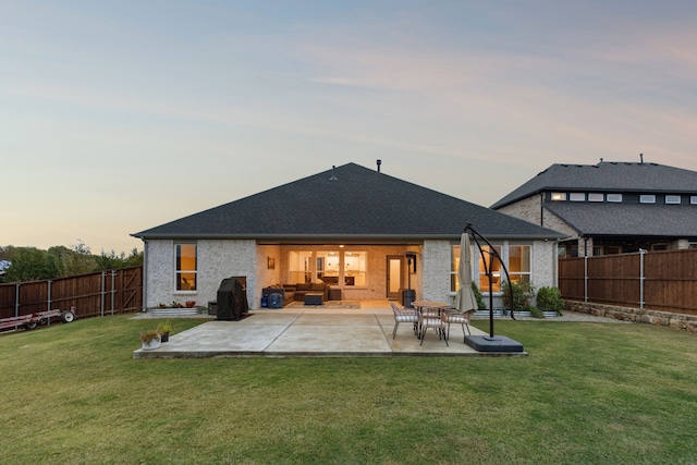 back house at dusk with a patio area and a yard