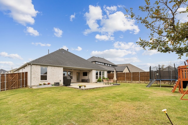 rear view of house featuring a yard, a patio, and a trampoline