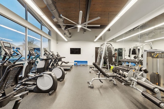 exercise room featuring ceiling fan, plenty of natural light, and a towering ceiling