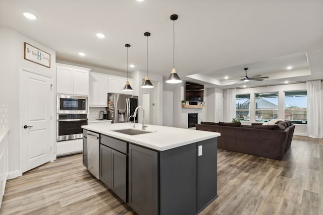 kitchen featuring white cabinetry, an island with sink, appliances with stainless steel finishes, and a tray ceiling