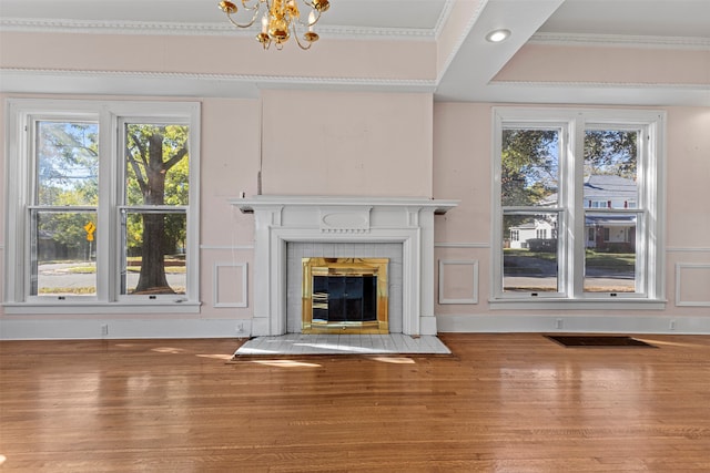 unfurnished living room with a tiled fireplace, hardwood / wood-style flooring, a healthy amount of sunlight, and crown molding