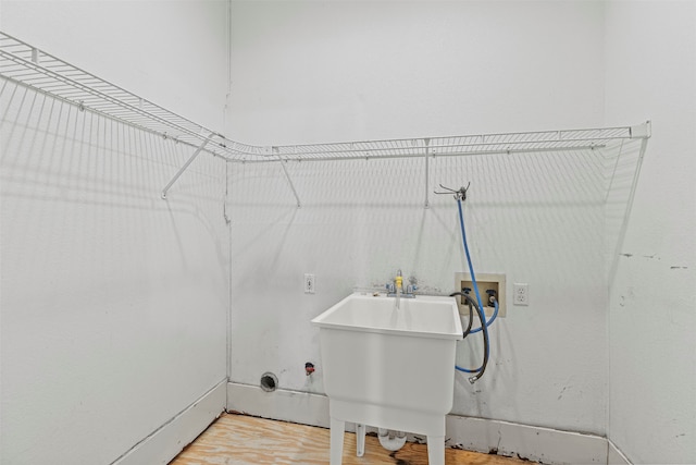 clothes washing area featuring hookup for a washing machine, sink, and hardwood / wood-style flooring