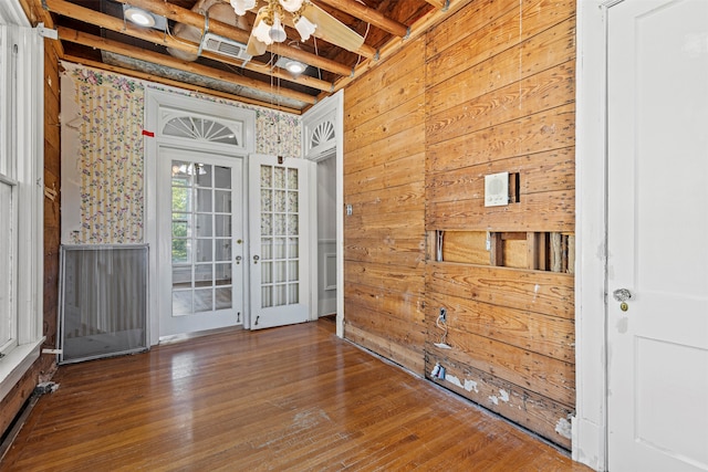 spare room featuring hardwood / wood-style floors, beamed ceiling, wood walls, and french doors