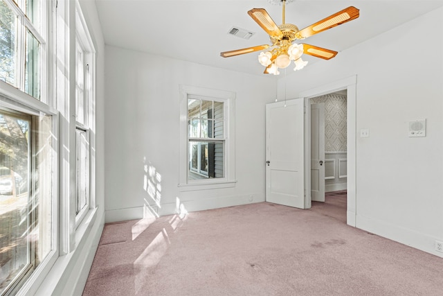 carpeted empty room with a wealth of natural light and ceiling fan