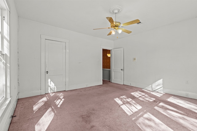 carpeted empty room featuring a wealth of natural light and ceiling fan