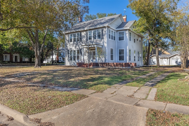 colonial home featuring an outbuilding, a front yard, and a garage