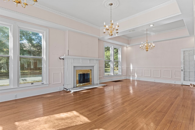 unfurnished living room featuring hardwood / wood-style floors, an inviting chandelier, and ornamental molding