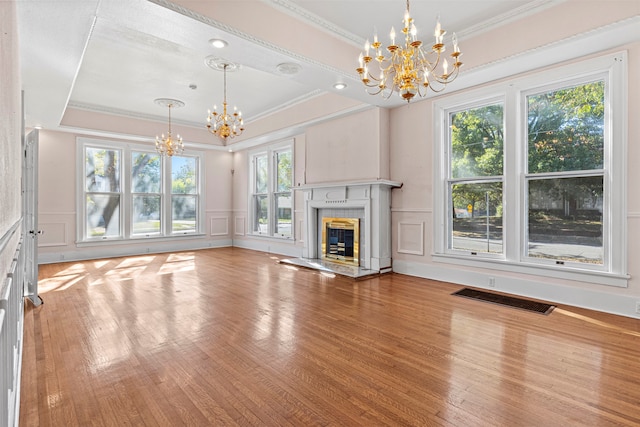 unfurnished living room featuring hardwood / wood-style flooring, an inviting chandelier, and crown molding