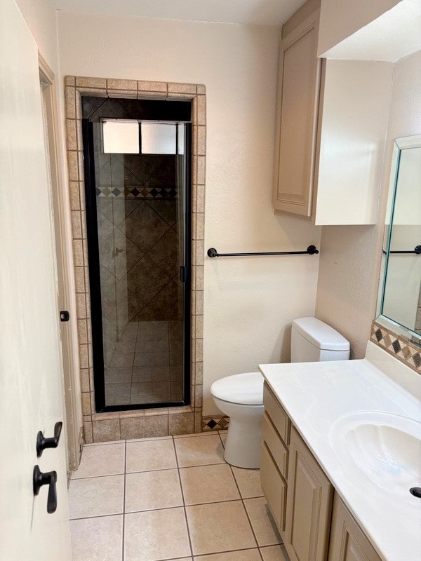 bathroom featuring tile patterned flooring, vanity, toilet, and a shower with shower door