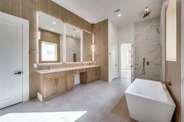 bathroom featuring tile walls, vanity, plus walk in shower, and concrete floors