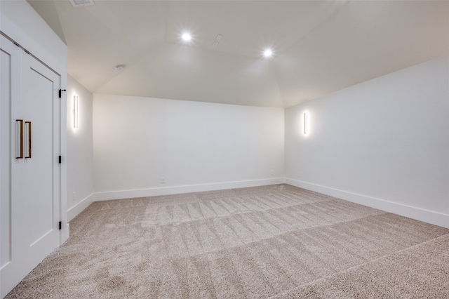 unfurnished room featuring light carpet and vaulted ceiling