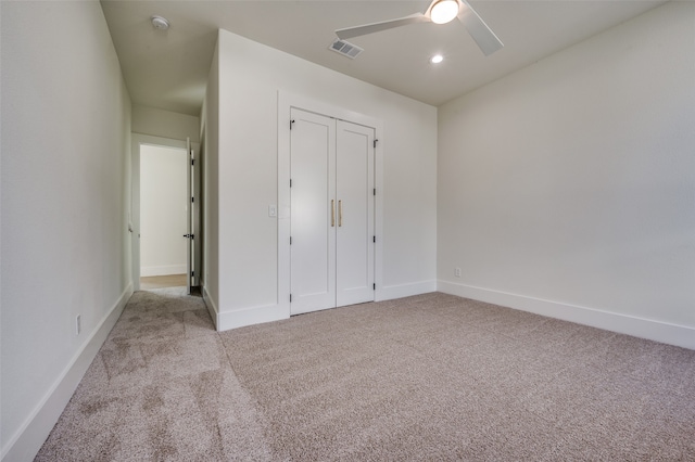 unfurnished bedroom featuring ceiling fan, a closet, and light colored carpet