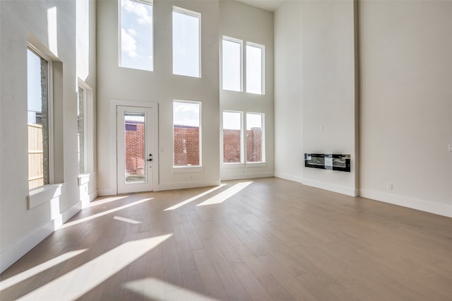 unfurnished living room featuring light hardwood / wood-style flooring and a high ceiling