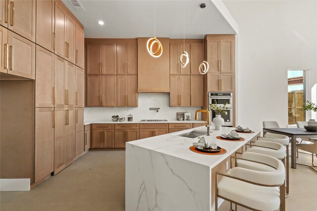 kitchen with sink, light stone countertops, gas cooktop, hanging light fixtures, and double oven