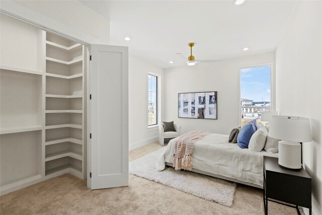 carpeted bedroom featuring multiple windows and ceiling fan