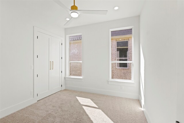 unfurnished bedroom featuring light colored carpet, ceiling fan, and a closet