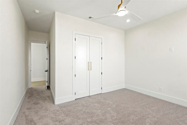 unfurnished bedroom with ceiling fan, light carpet, and a closet