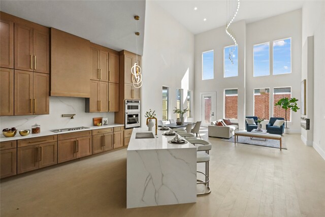 kitchen featuring a high ceiling, sink, stovetop, a breakfast bar area, and double oven