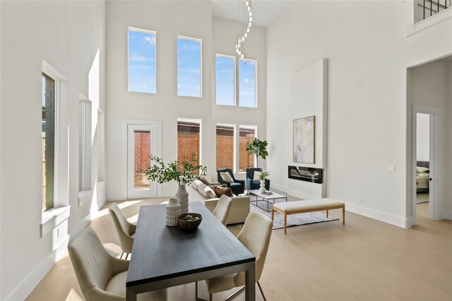 dining space with a towering ceiling and light hardwood / wood-style floors