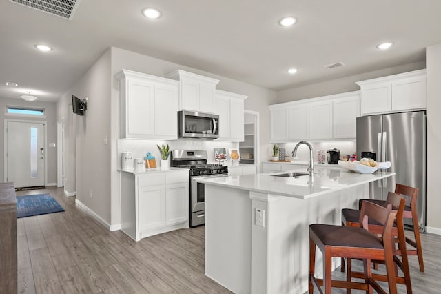 kitchen featuring white cabinetry, sink, appliances with stainless steel finishes, a breakfast bar area, and light wood-type flooring