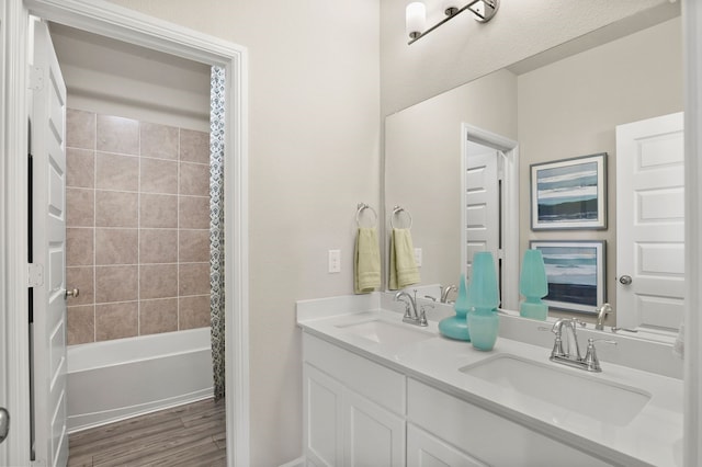 bathroom with hardwood / wood-style flooring, vanity, and tiled shower / bath combo