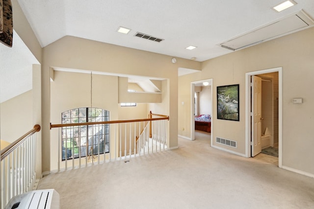 hallway featuring light colored carpet and lofted ceiling