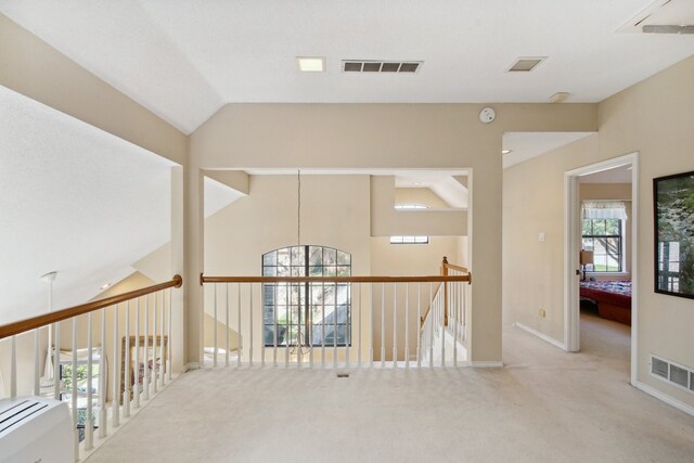 hall with light carpet, high vaulted ceiling, and a notable chandelier