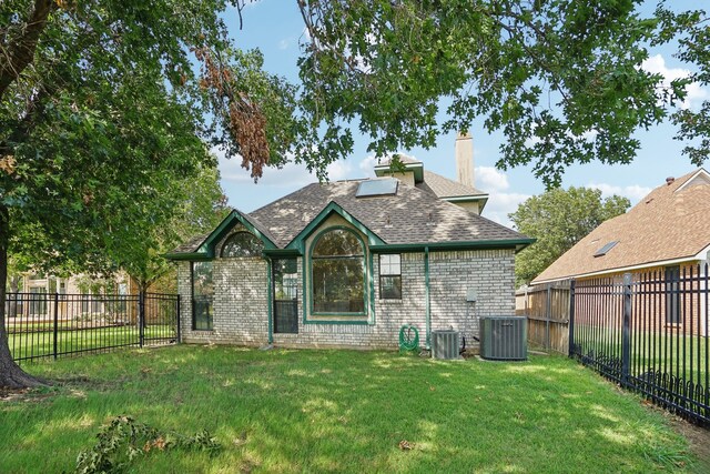 back of property with central AC unit and a yard