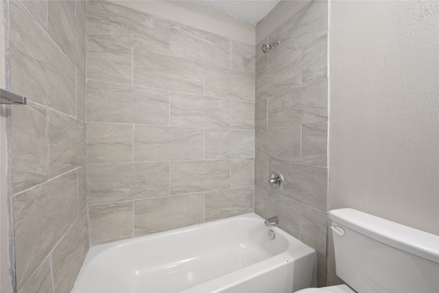 bathroom featuring toilet, tiled shower / bath, and a textured ceiling