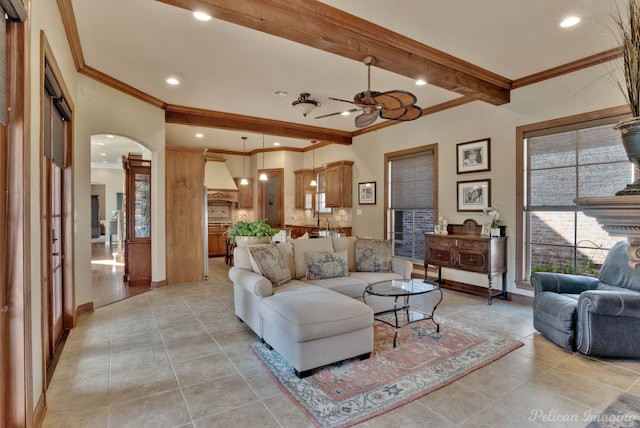 tiled living room with ornamental molding, ceiling fan, and beam ceiling