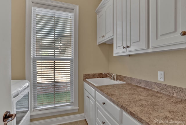 laundry area featuring cabinets, light tile patterned floors, and sink