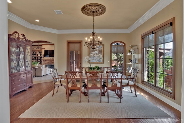 dining space featuring an inviting chandelier, plenty of natural light, light wood-type flooring, and ornamental molding