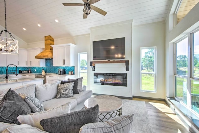 living room with a fireplace, light hardwood / wood-style flooring, sink, wooden ceiling, and ceiling fan with notable chandelier