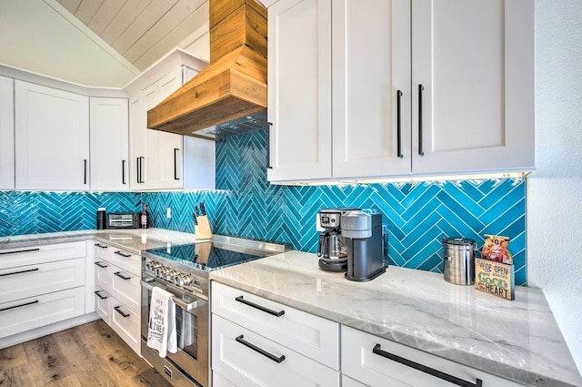 kitchen with wood-type flooring, light stone counters, double oven range, white cabinetry, and custom exhaust hood