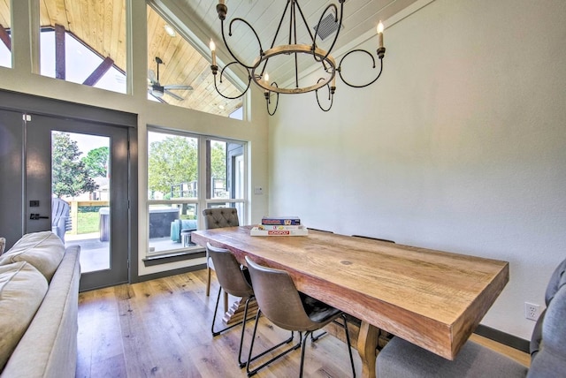 dining room featuring ceiling fan with notable chandelier, wood ceiling, light hardwood / wood-style flooring, and high vaulted ceiling